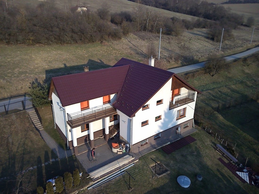 Rodinný dom s hotovou tmavou škridlovou strechou, pohľad z dronu